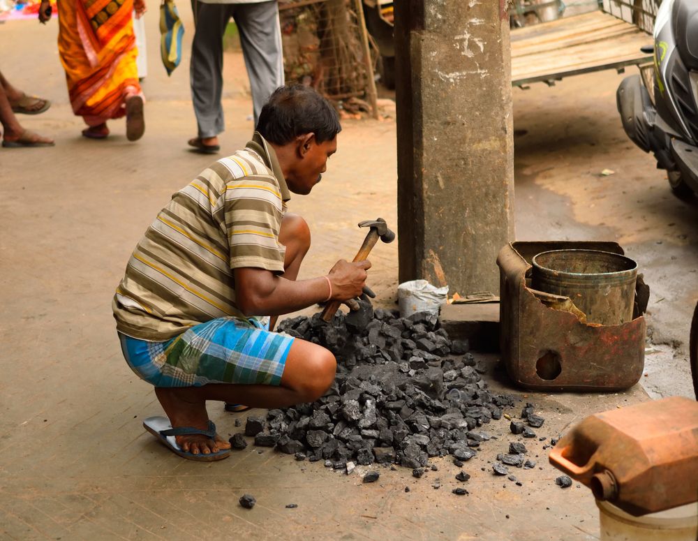 Kolkata, India, March 2017. A man breaking coal with a hammer.