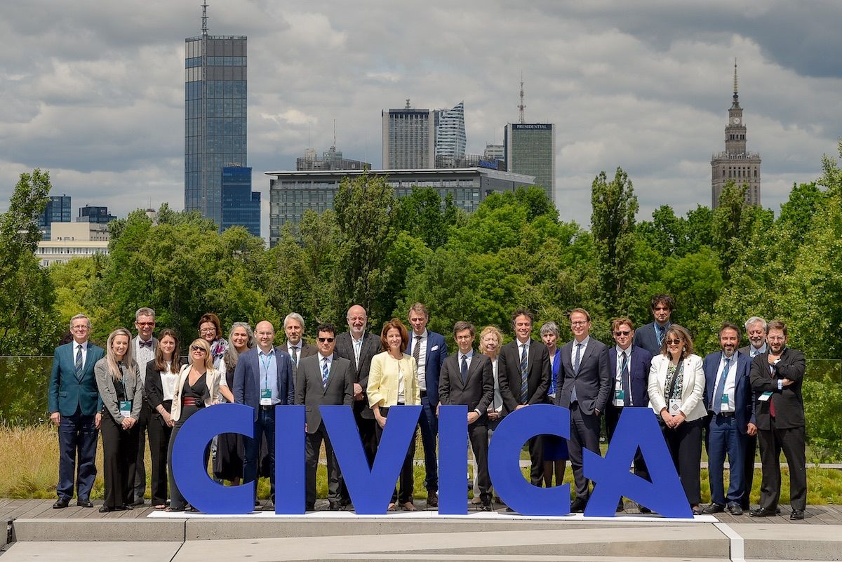 CIVICA partners' presidents and team at SGH Warsaw, behind the CIVICA logo, in a park