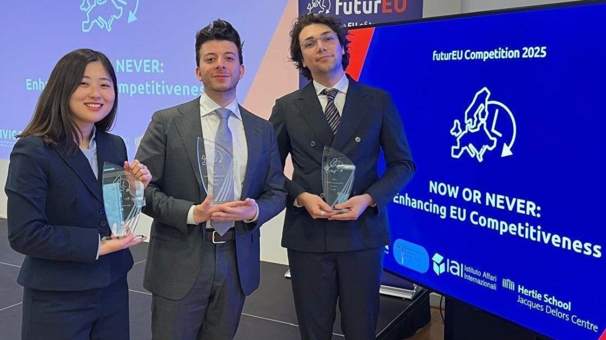 The three winners in front of a screen where the topic is written "Now or Never: Enhancing EU Competitiveness".