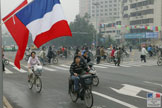 Drapeaux français et chinois dans une rue fréquentée par des cyclistes à Chengdu