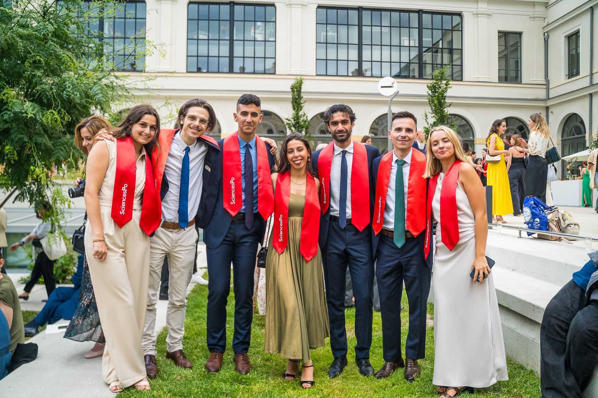 Groupe d'étudiants diplômes avec écharpes rouges pendant le cocktail