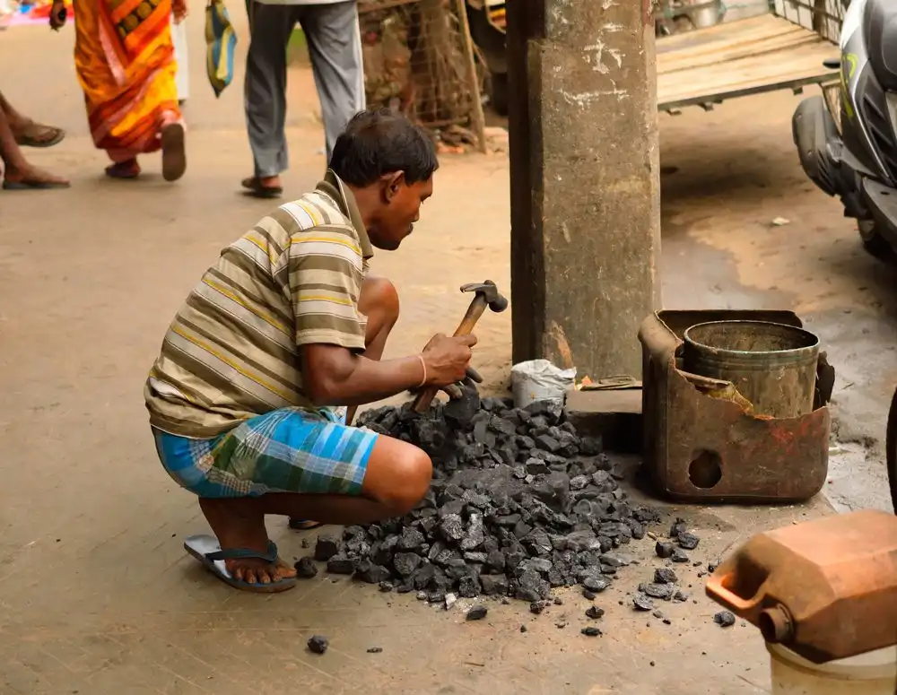 Kolkata, India, March 2017. A man breaking coal with a hammer.