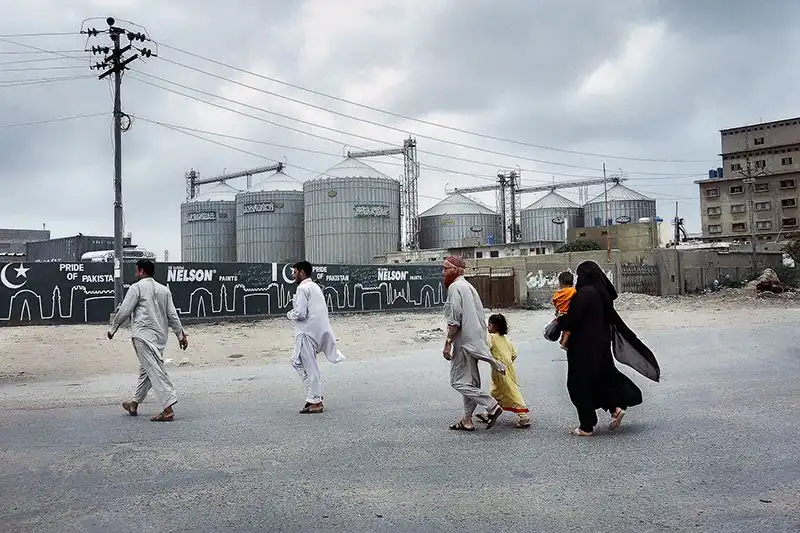 Famille ouvrière traversant l'un des principaux axes routiers dans la zone industrielle de Korangi.
