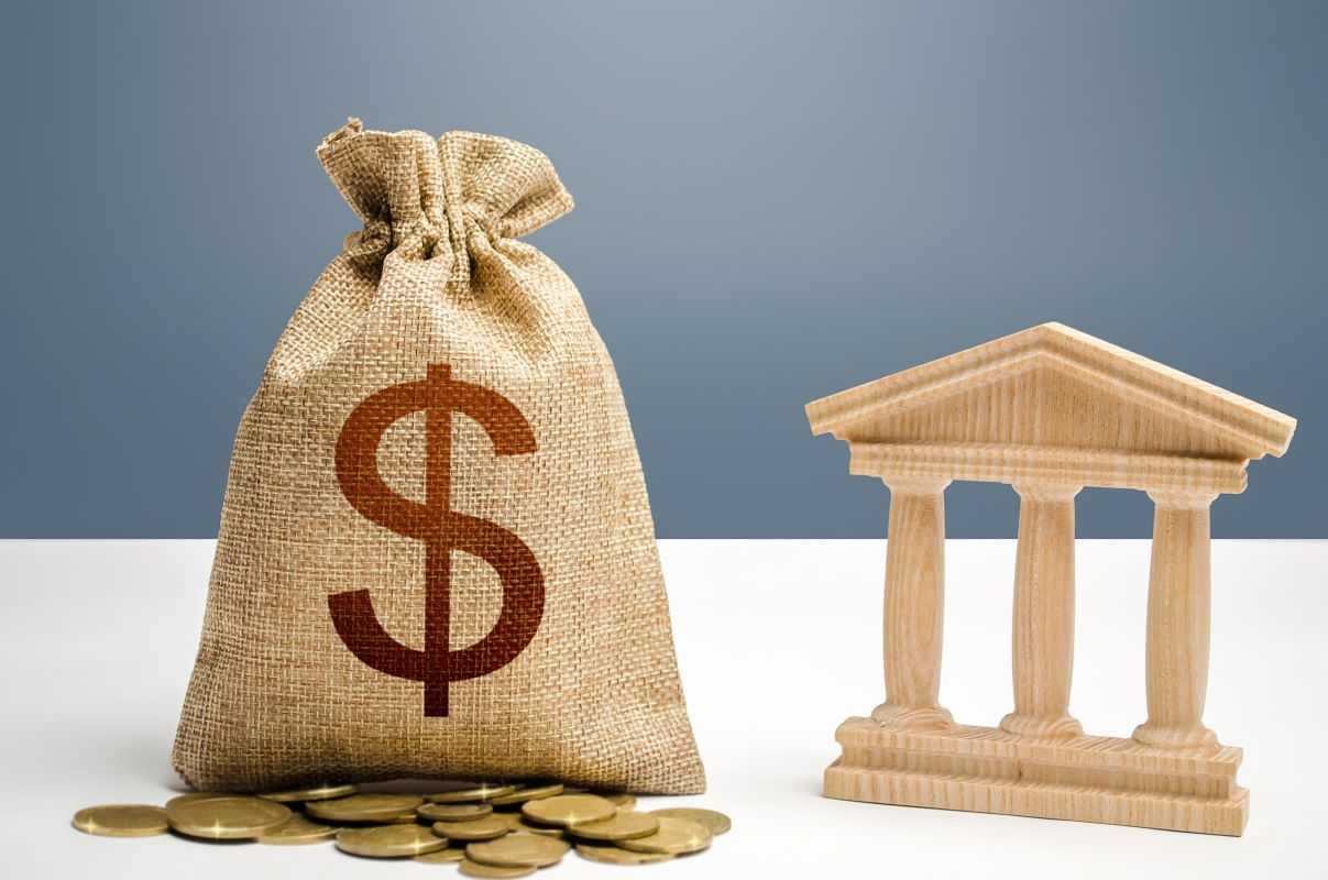 A bag of dollar bills and a bank building