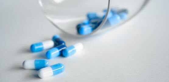 Médicaments bleus et blancs qui débordent d'un verre couché