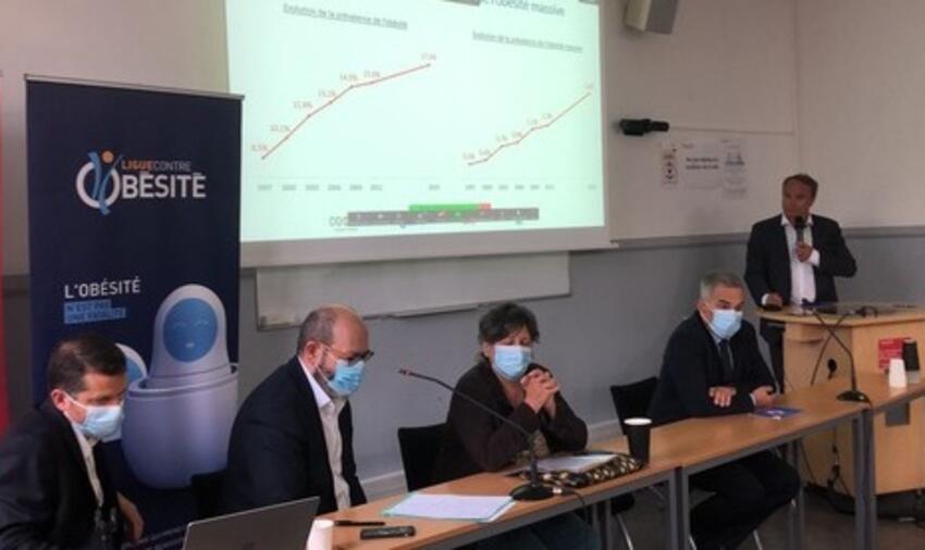 Les conférenciers assis avec un écran projeté et un kakémono de la LCO