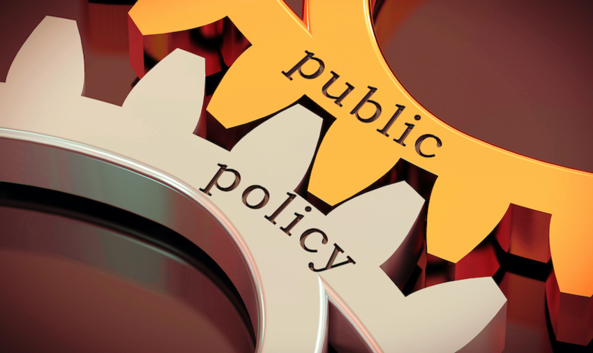 Two cogs fitting together on which public policy is written