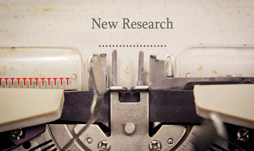 Paper in typewriter on which is printed "New Research"