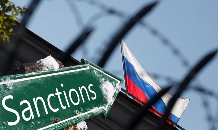 Sign indicating "Sanctions" pointing to Russian flag behind barbed wire