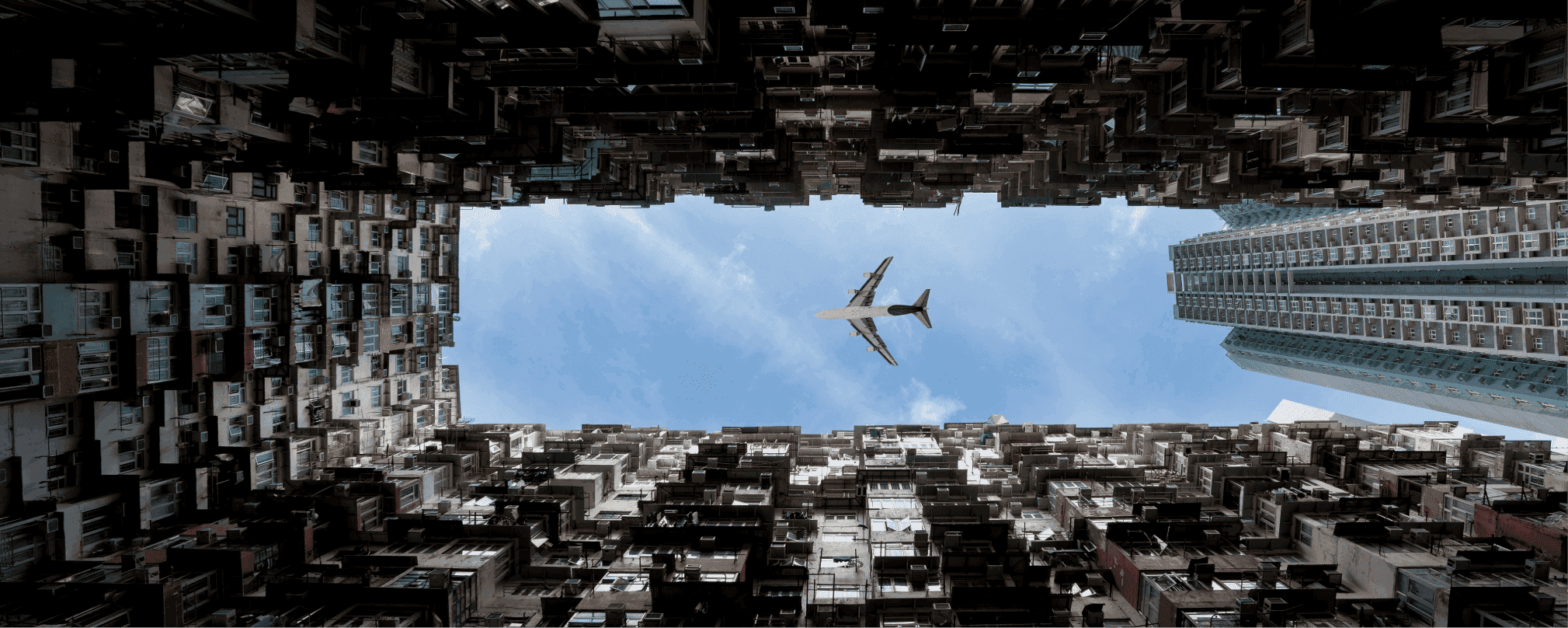 An airplane seen from below amid skyscrapers