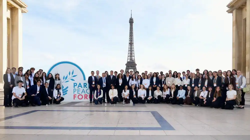 Volunteers’ family photo at Palais de Chaillot with Paris Peace Forum’s Logo and the Eiffel Tower in the background.