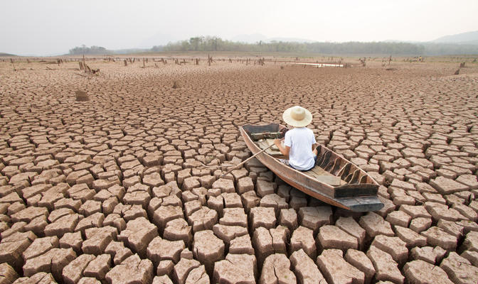 Climate change, The man on wood boat at large drought land by Piyaset, Shutterst