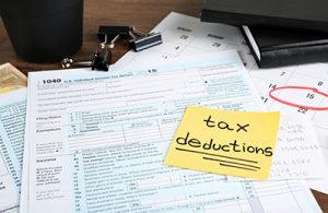 Paper sheet with text TAX DEDUCTIONS and individual tax return form on table. Crédits : Shutterstock